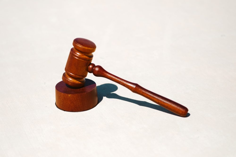 A wooden gavel rests on a matching sound block against a plain light background, symbolizing the weight of justice in cases involving punitive damages. The gavel is positioned with the head angled slightly upward, casting a shadow.